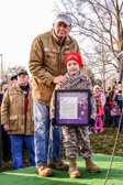 Morrill Worcester's grandson holding award containing appreciation letter and challenge coins from Marine Corps Sergeant Major Bryan B. Battaglia and Martin E. Dempsey, Head of the Joint Chiefs of Staff