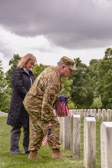Chief of Staff of the Army General Mark A. Milley places a flag at a fallen soldiers grave while  his wife Hollyanne solemnly looks on.