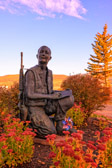 On Memorial Day 2003, Taos artist Doug Scott dedicated his interpretation of a soldier's dilemma of writing home from war. This life-size statue depicts an American infantryman in the field. A small ammo box is the best chair he can find, and his helmet is the best backing available for writing a letter to his parents. What can he say about what he's doing that they will understand?