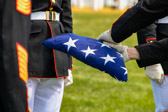 The folded flag is passed along to the awaiting officer for presentation to the family member.